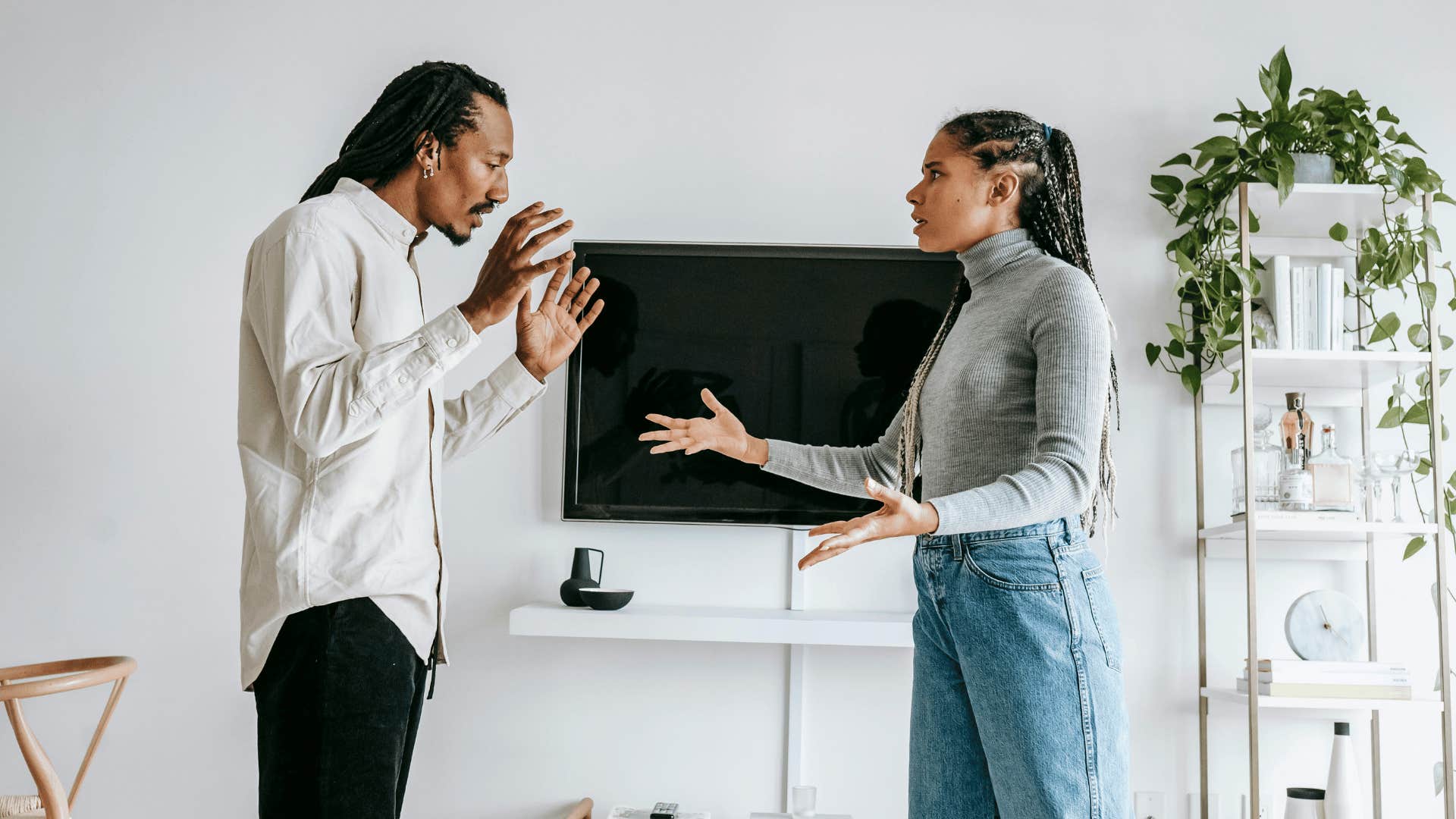 man holding hands up towards upset woman