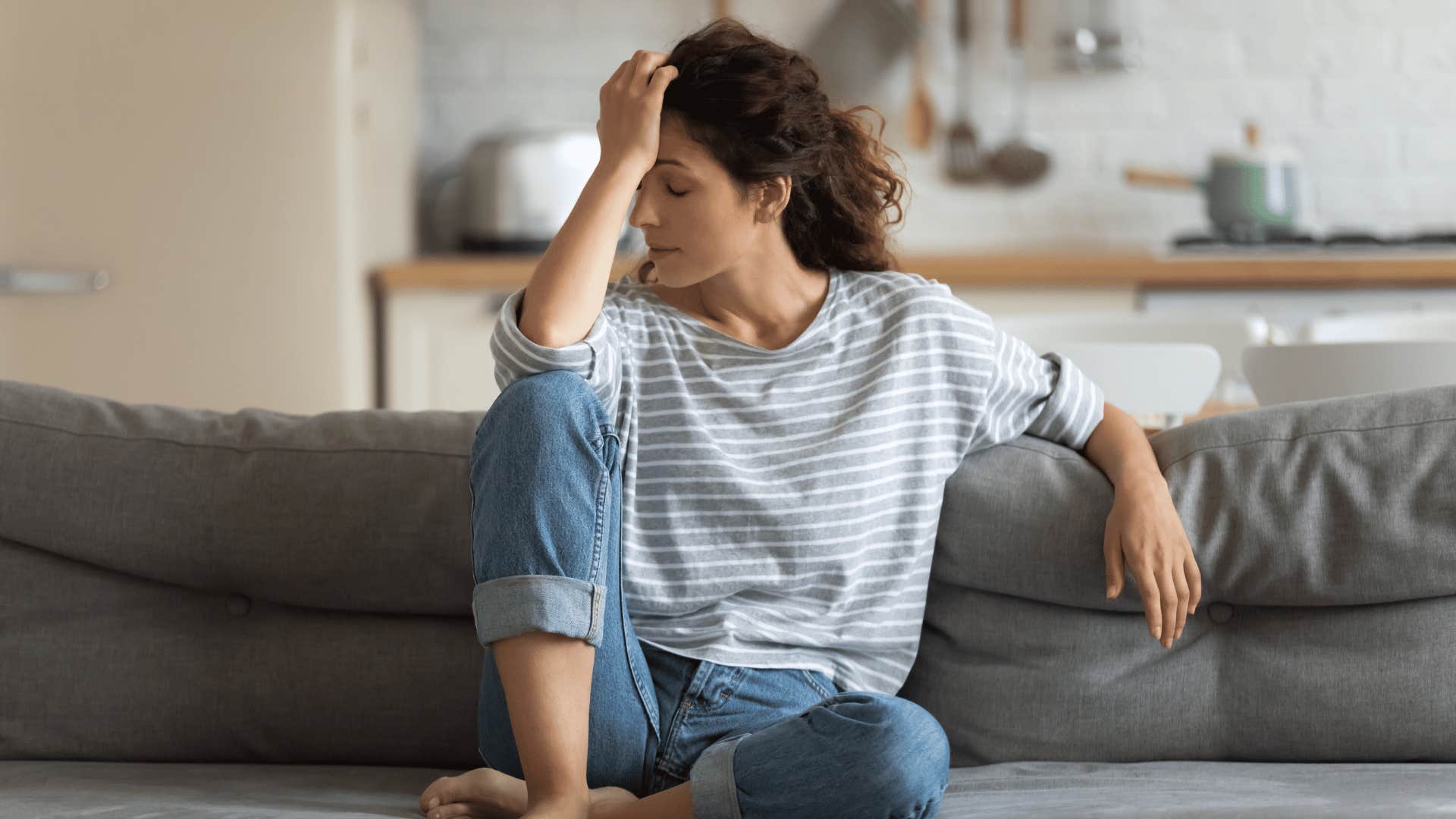 upset and stressed woman sitting on couch