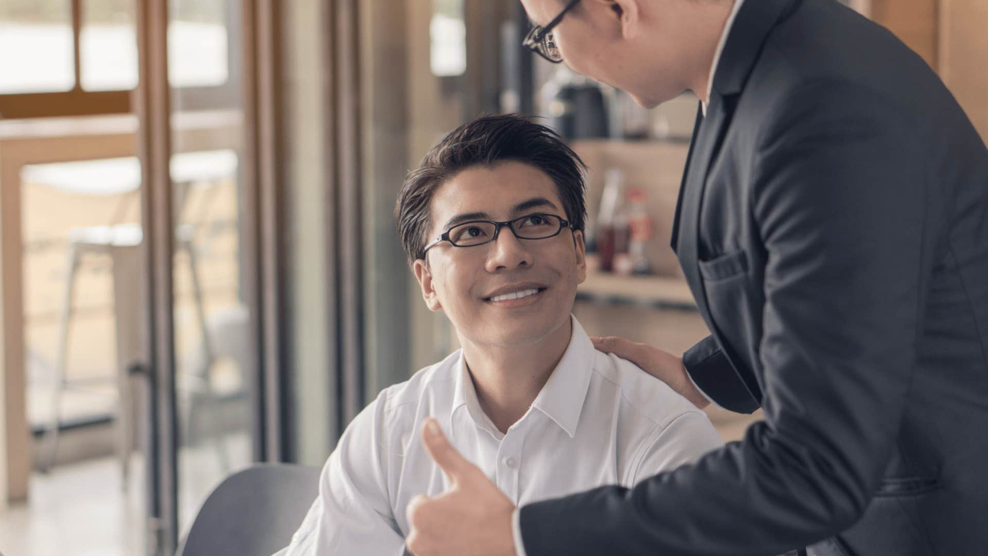 coworker giving thumbs up to smiling younger man