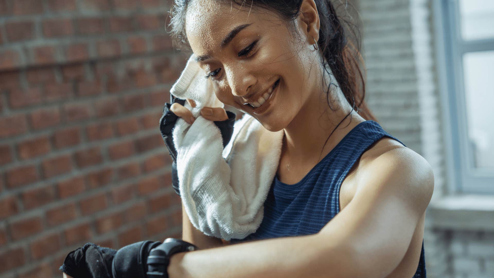 woman using towel to dry sweat from workout