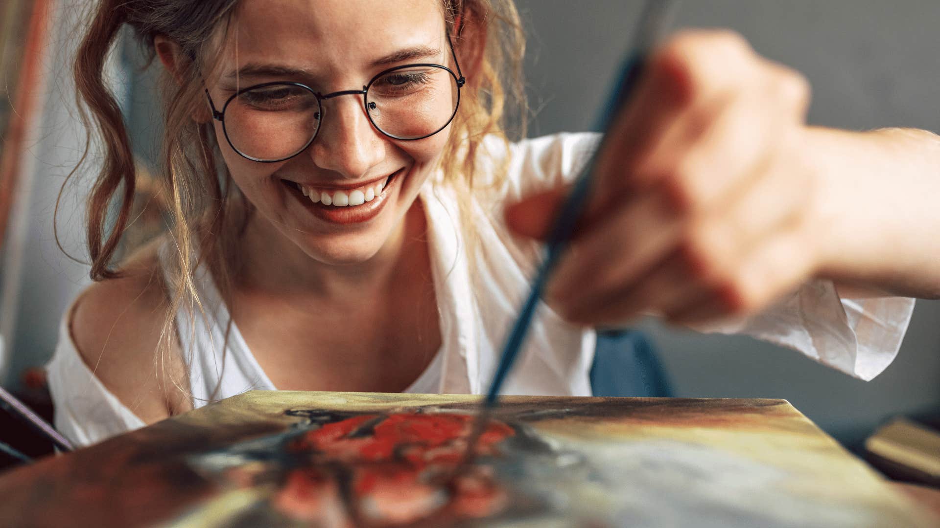 closeup of smiling young woman who is painting