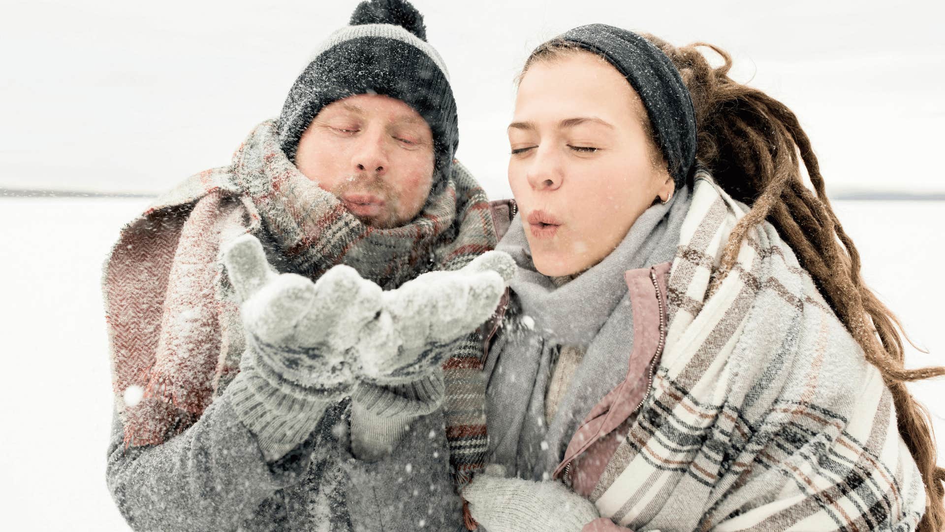 couple blowing snow out of hands