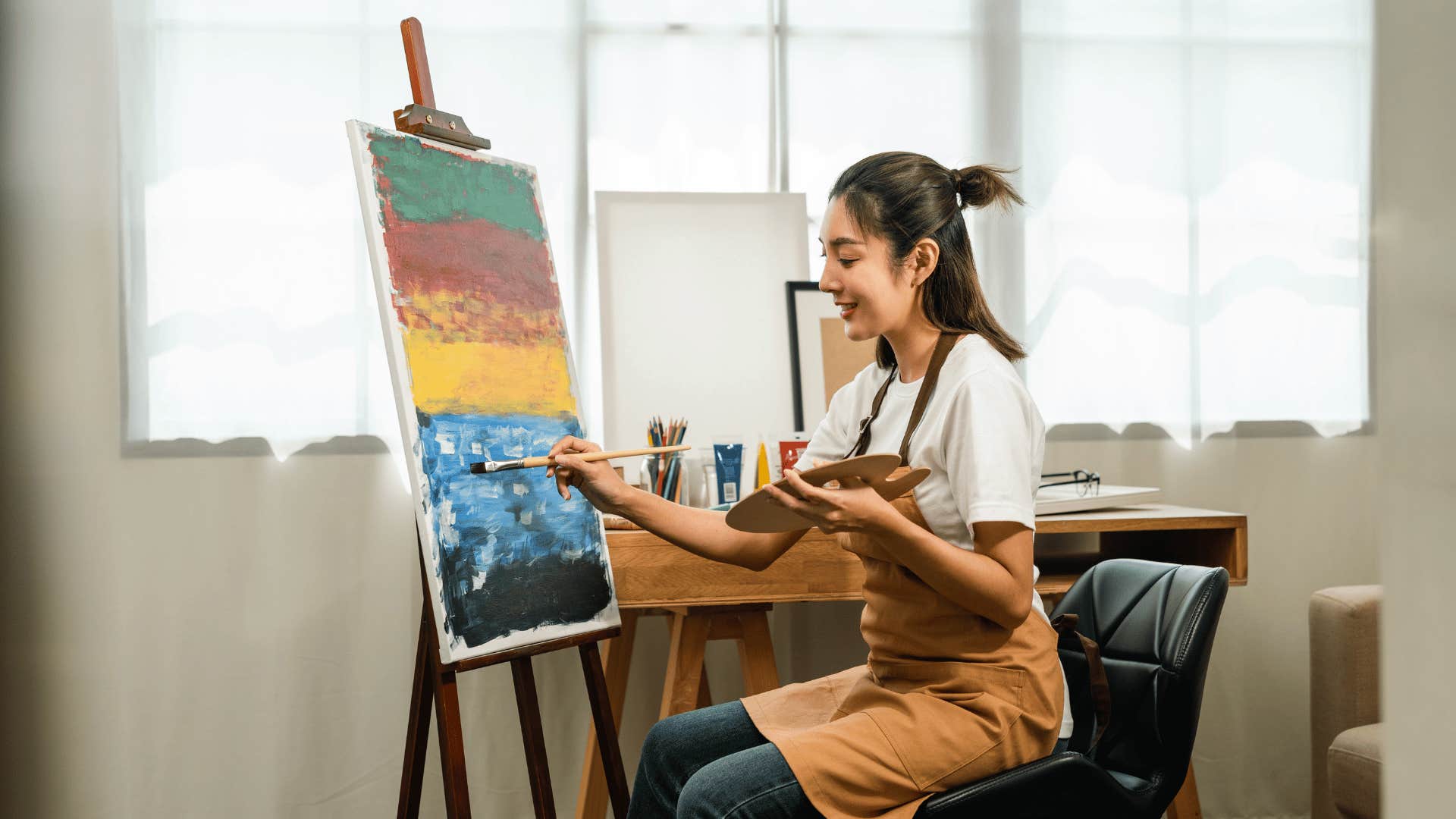 smiling woman painting on a canvas