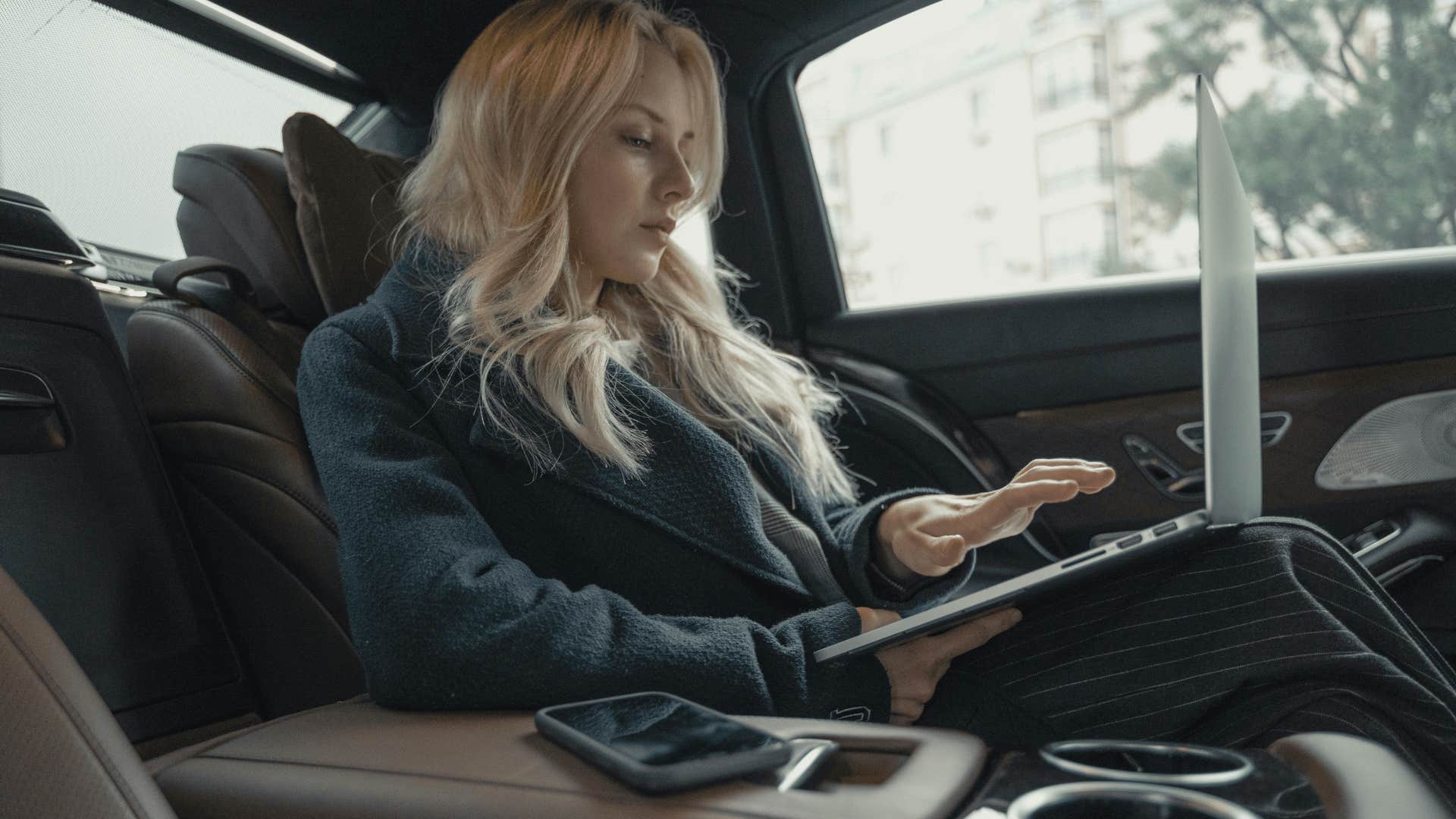 woman working on laptop inside car