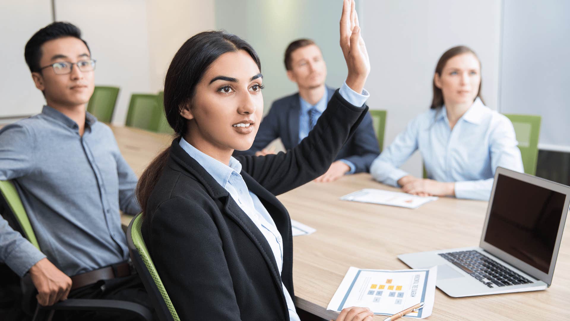 young woman raising her hand during team meeting