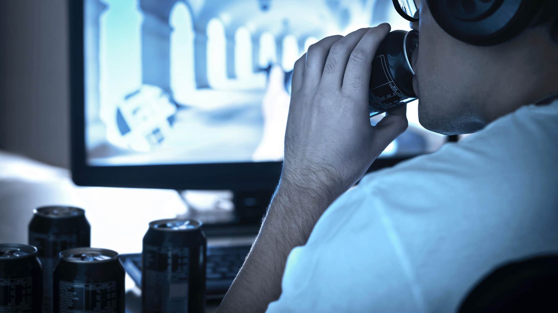 man playing video games with several energy drinks