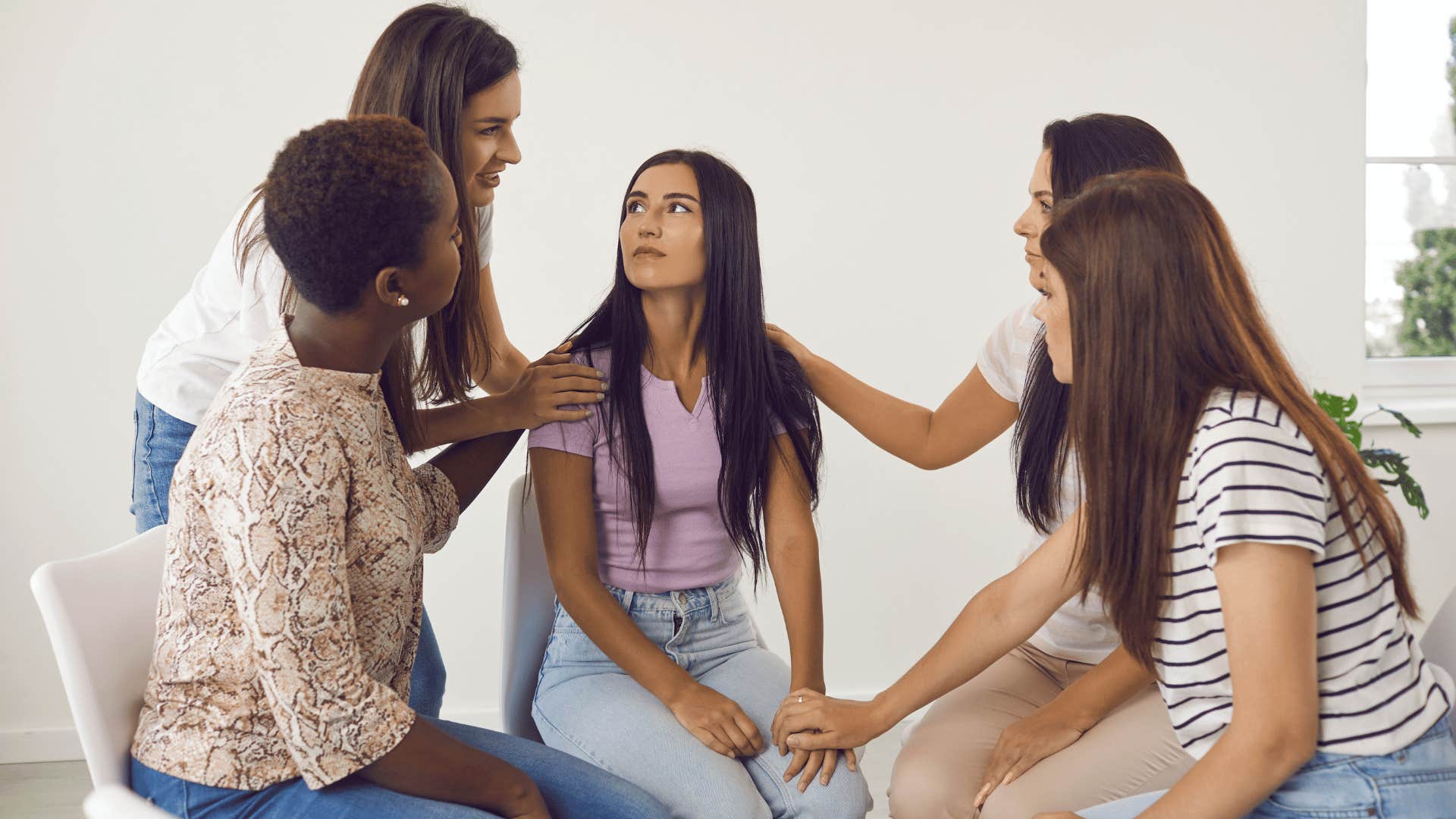 group of women comforting young woman