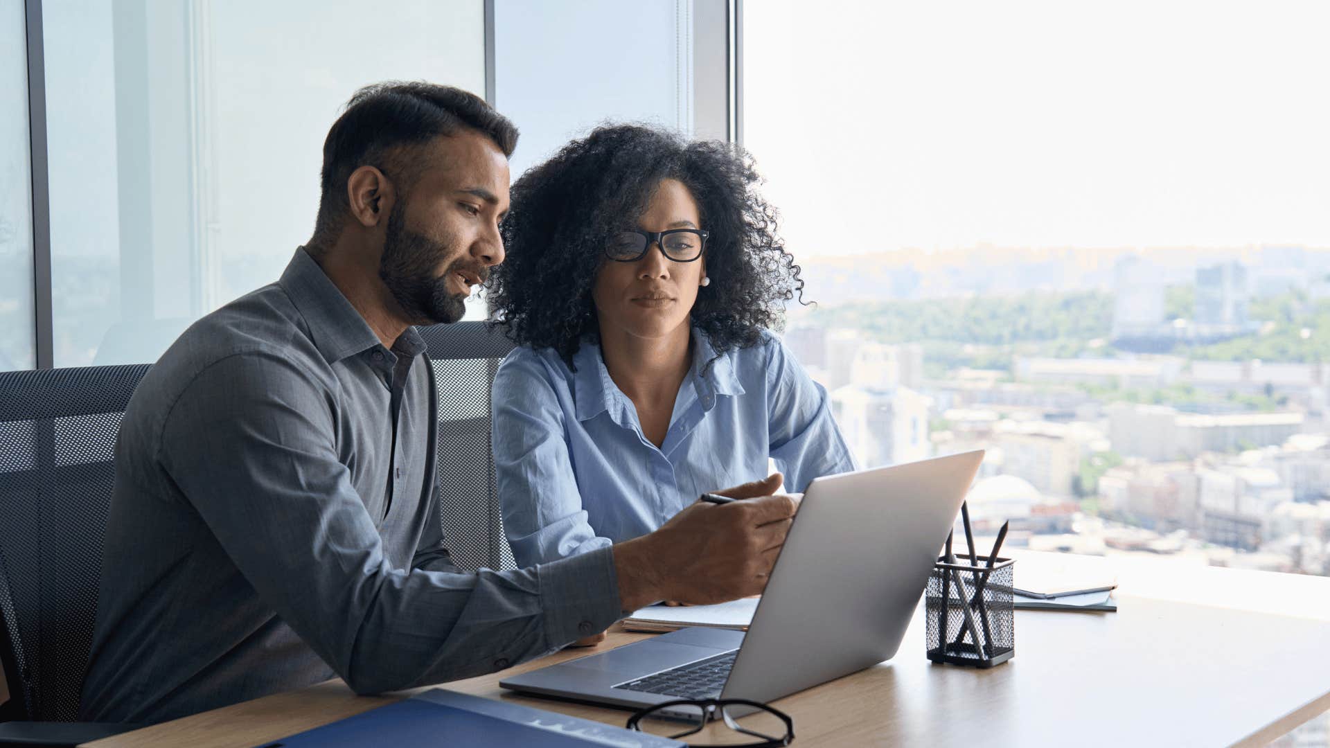 man pointing at something on laptop to woman