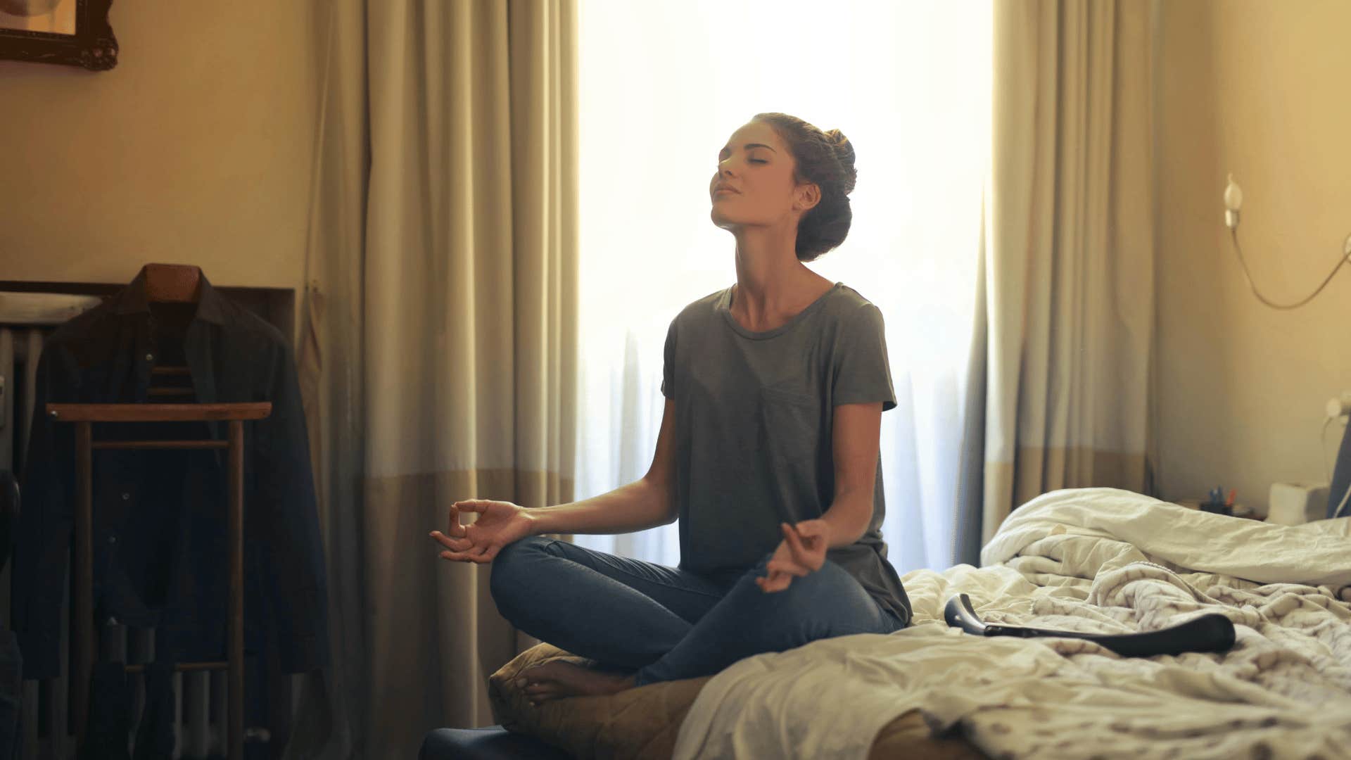 woman meditating on edge of bed