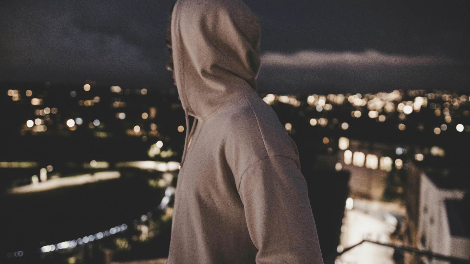 man in a gray hoodie standing on a rooftop