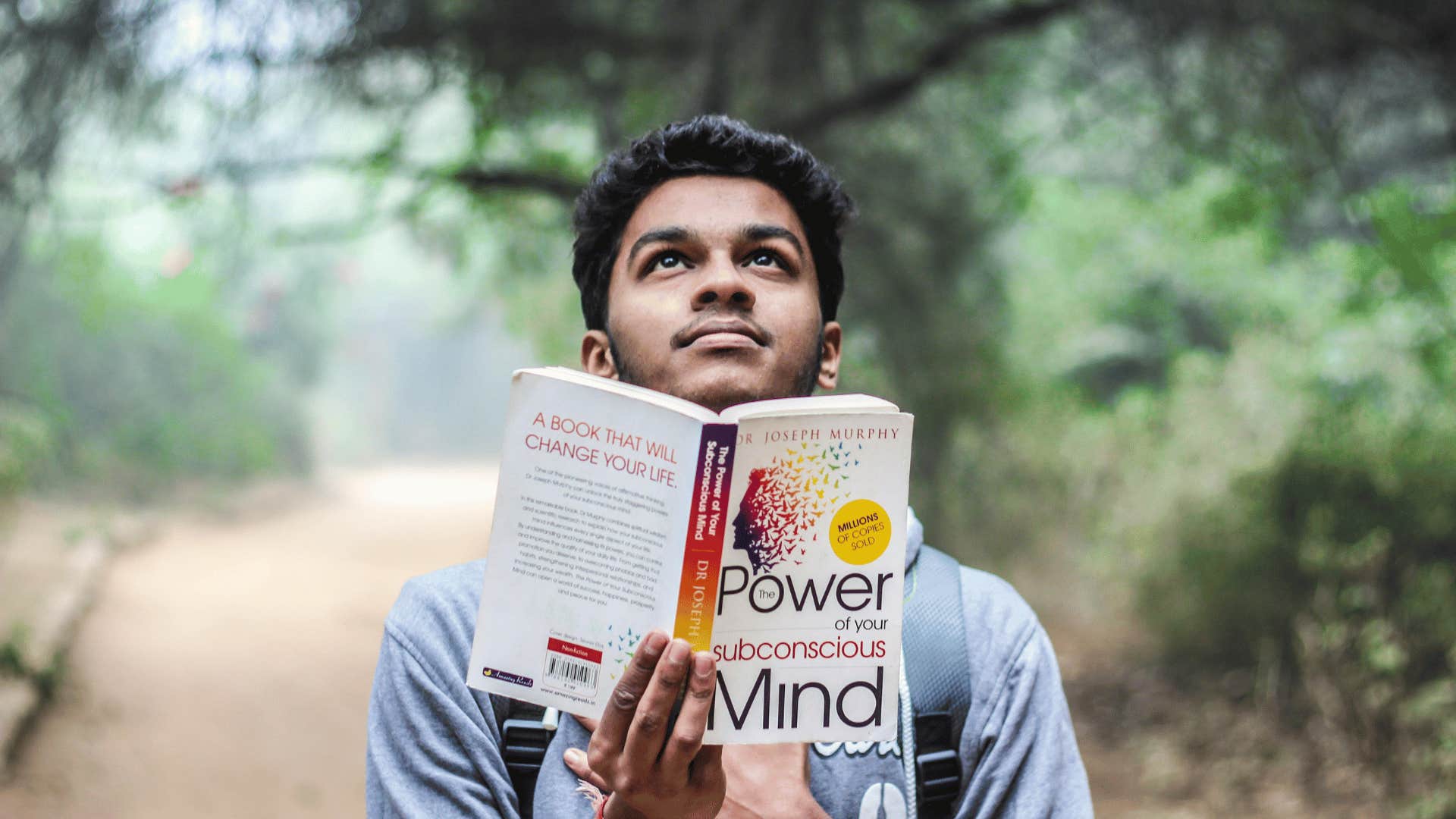 man looking up and reading book outdoors