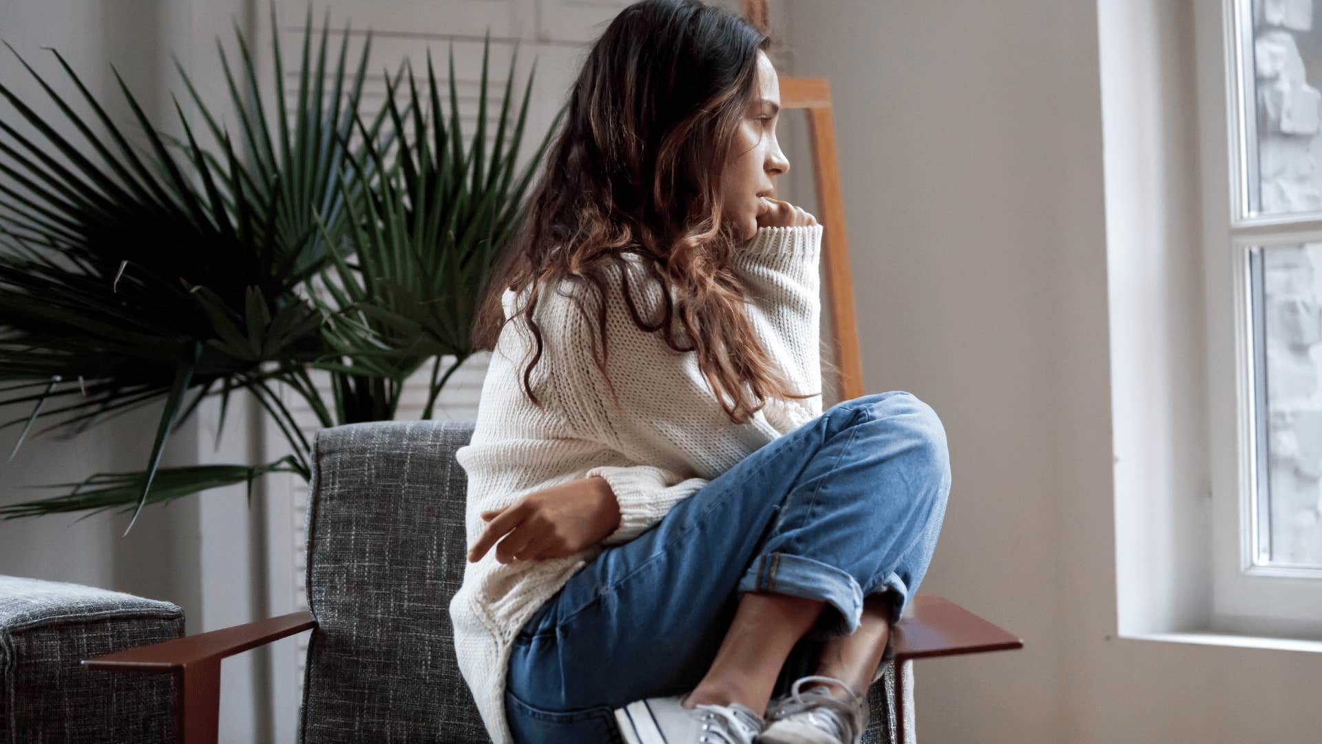 woman curled up in a chair looking out of a window