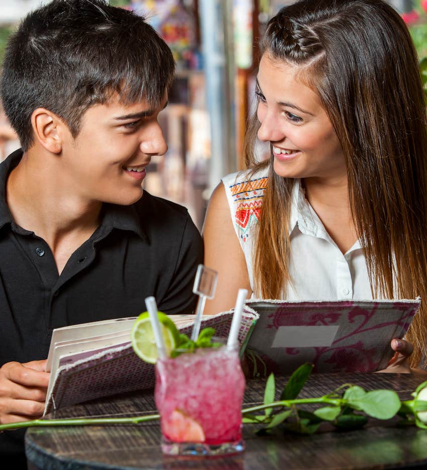 They share eye contact and a smile over a menu