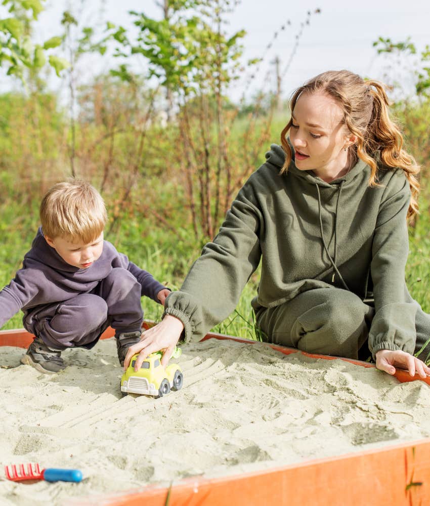 Babysitter and little boy playing in sandbox