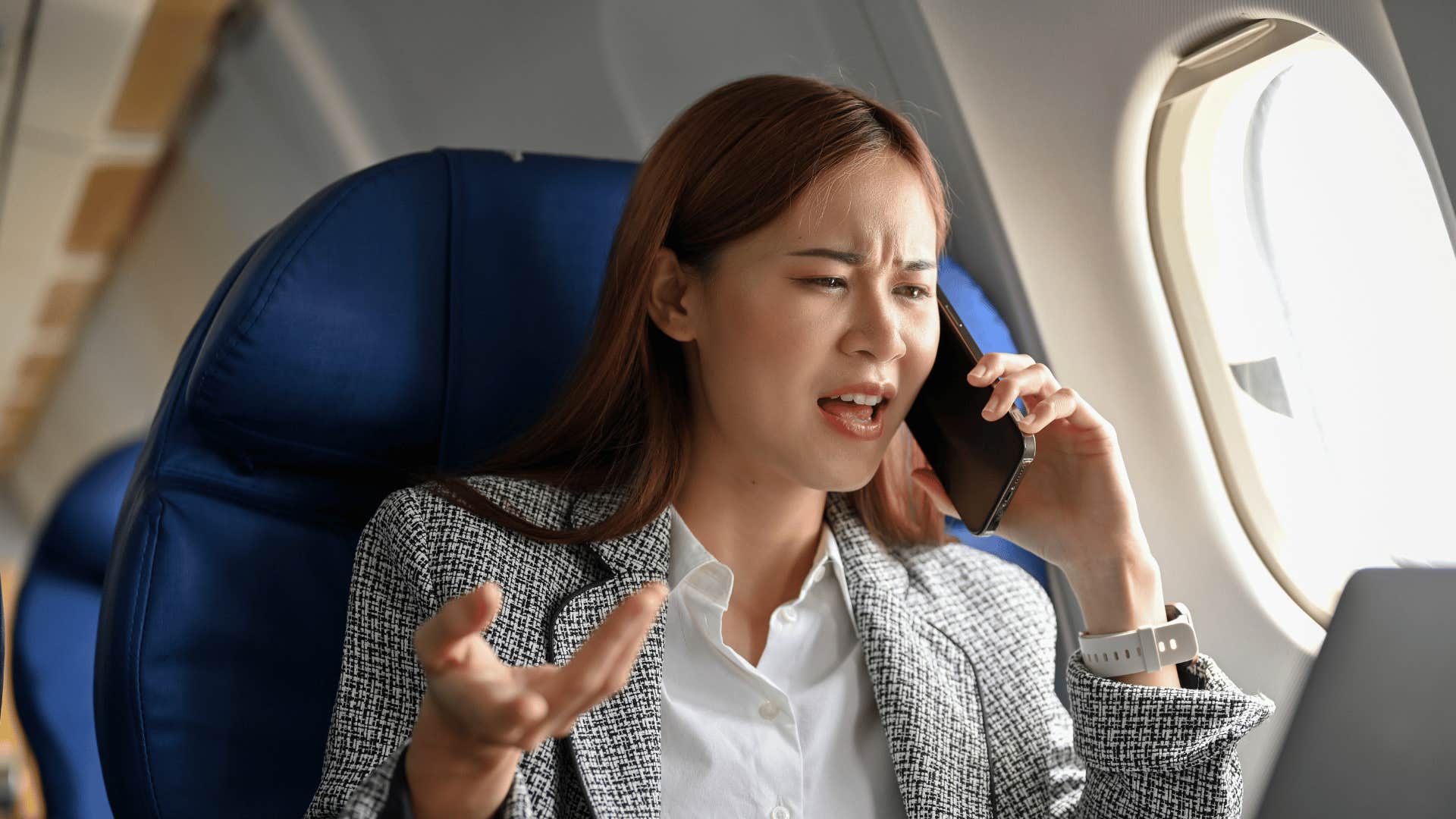 annoyed woman talking on phone on plane