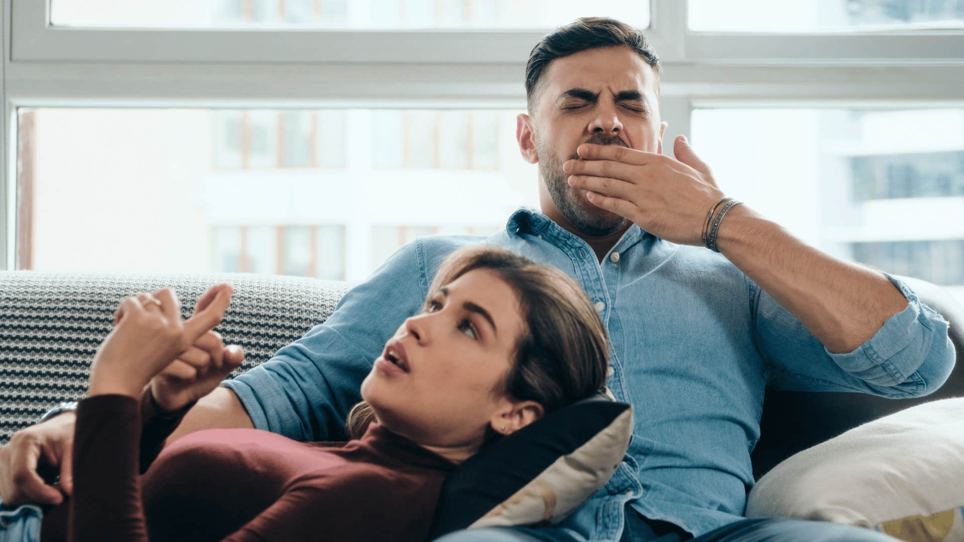 man yawning while woman talks