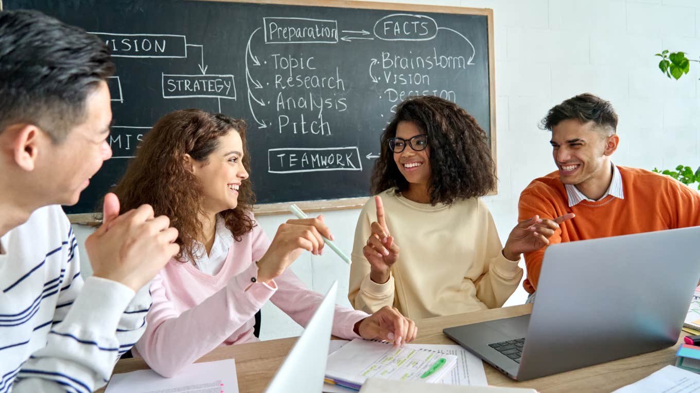 gen z employees smiling while sitting around table at work