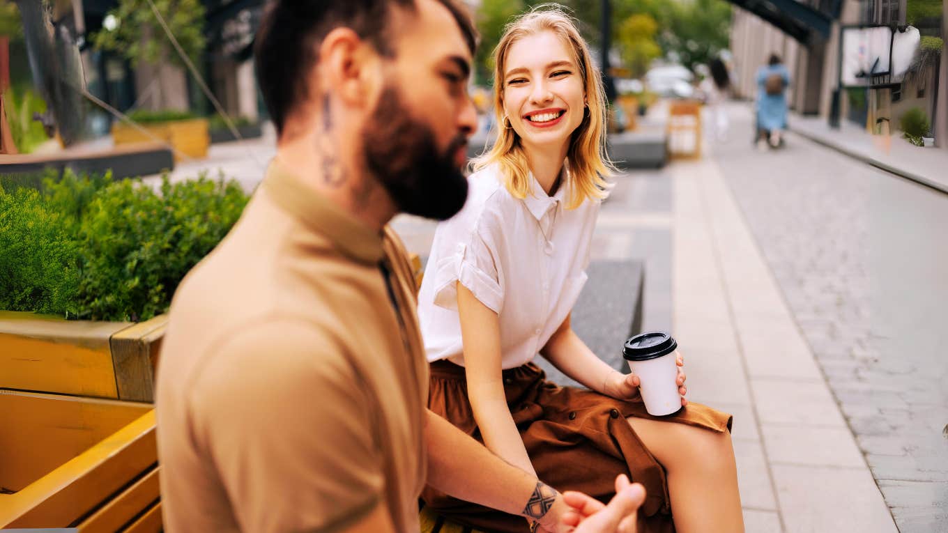 Woman charming a rather intimidating guy on bench 