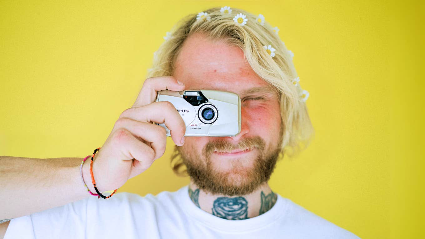 Millennial man holding a old school digital camera