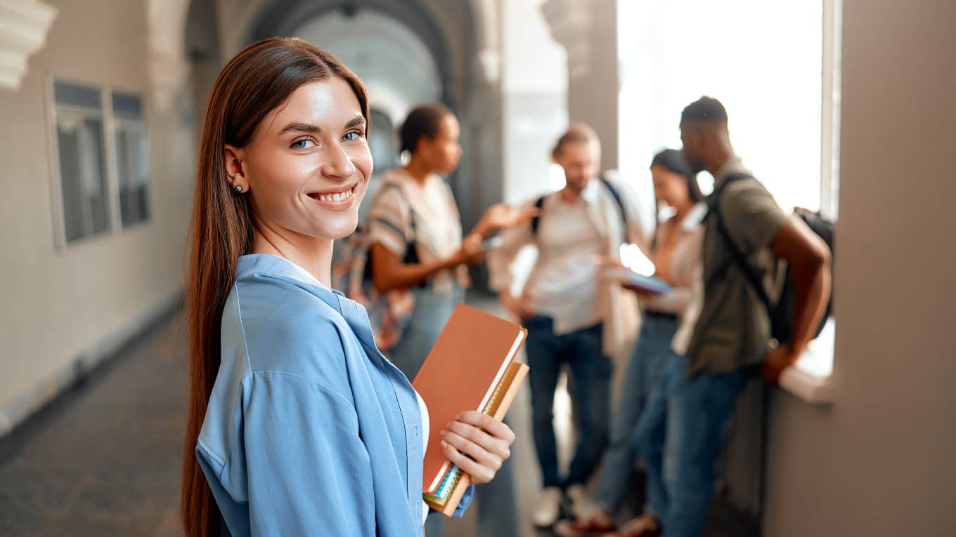 college student standing by herself near a group of students