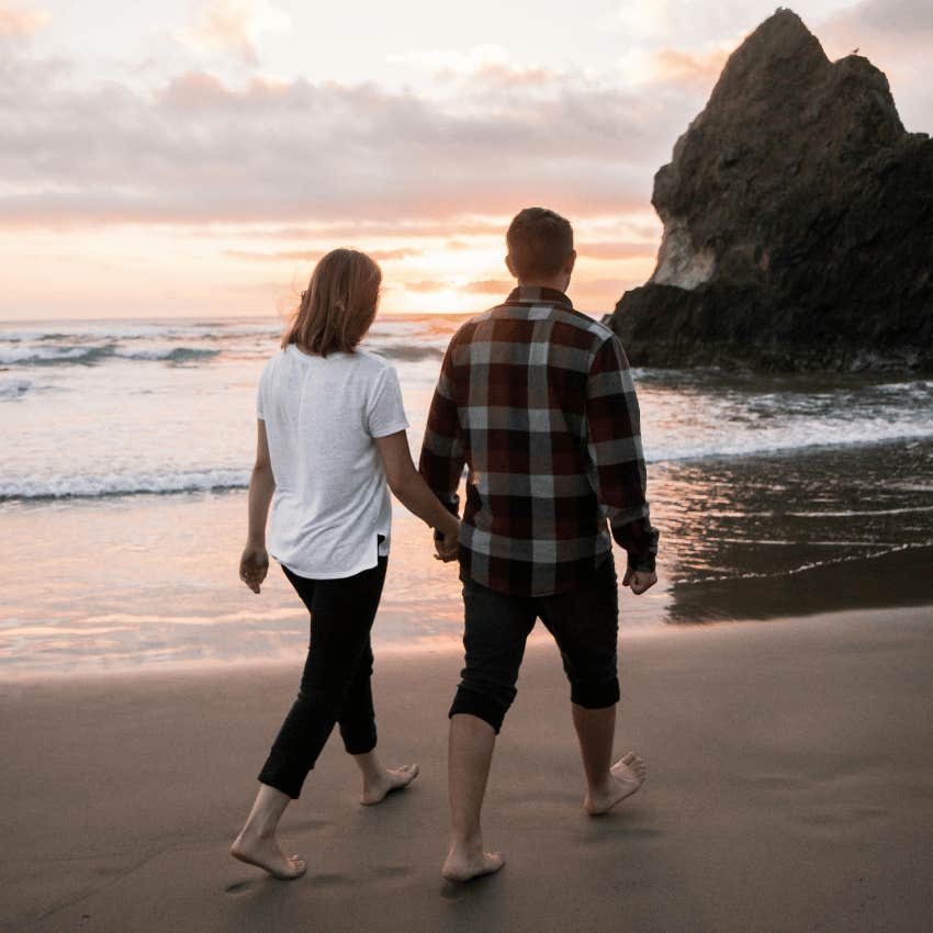 couple holding hands and walking on beach