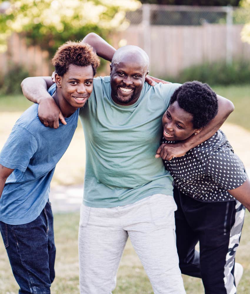 Dad with arms around two tween sons