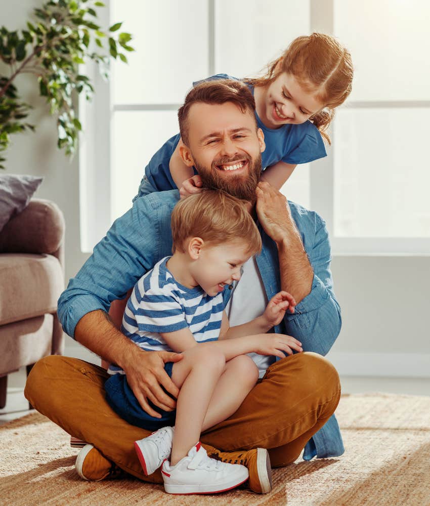 dad smiling while wrangling his son and daughter