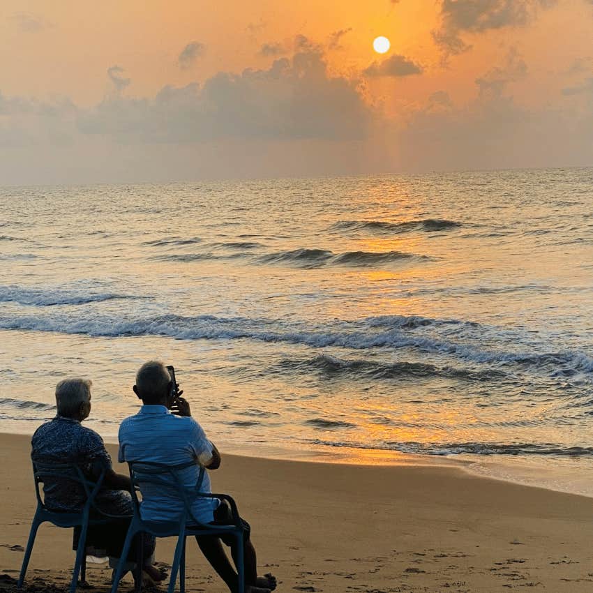 elderly couple sitting on the beach