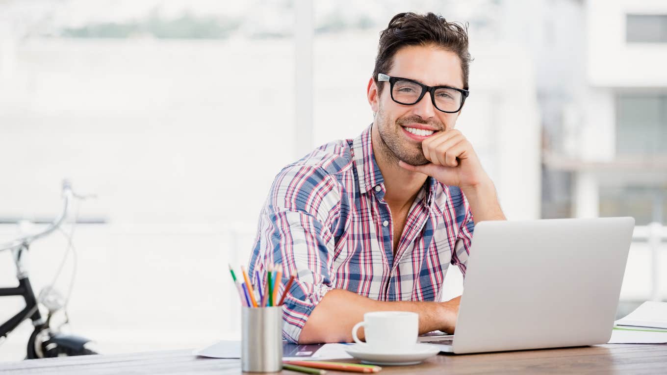 Smiling man sending farewell email to co-workers