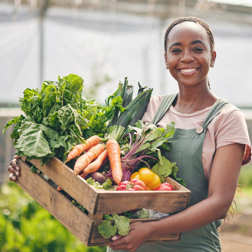 Worker in the farming career field smiling with vegetables. 