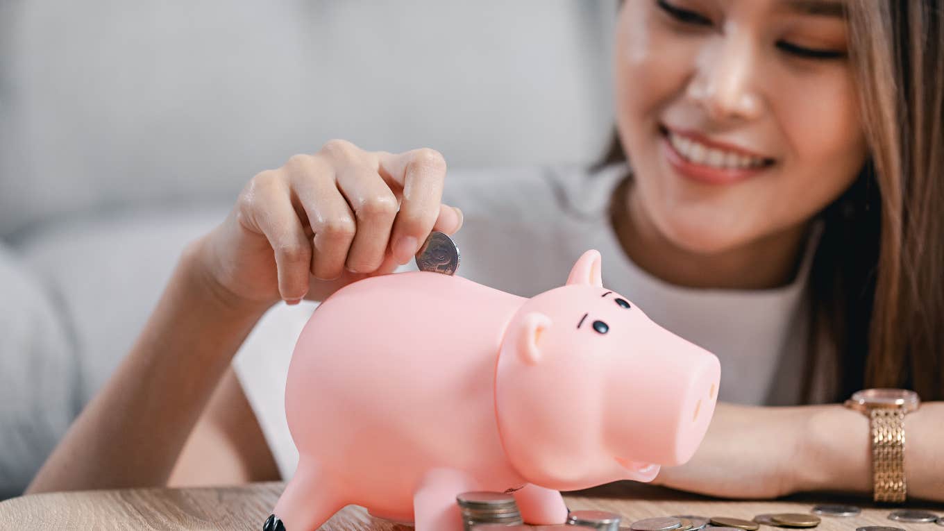 Woman putting money in her piggy bank