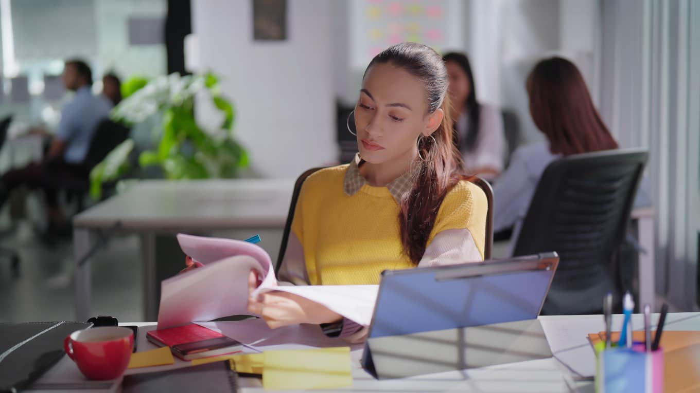 gen z employee reading paperwork at desk