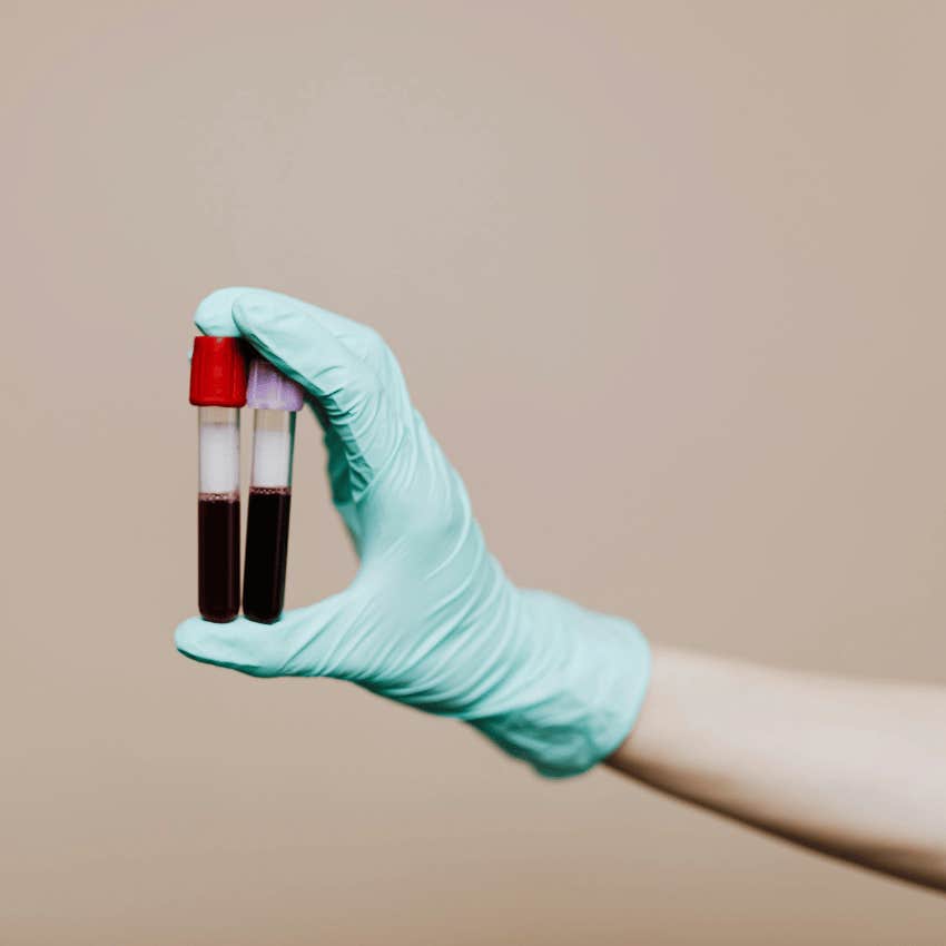 gloved hand holding tubes of blood