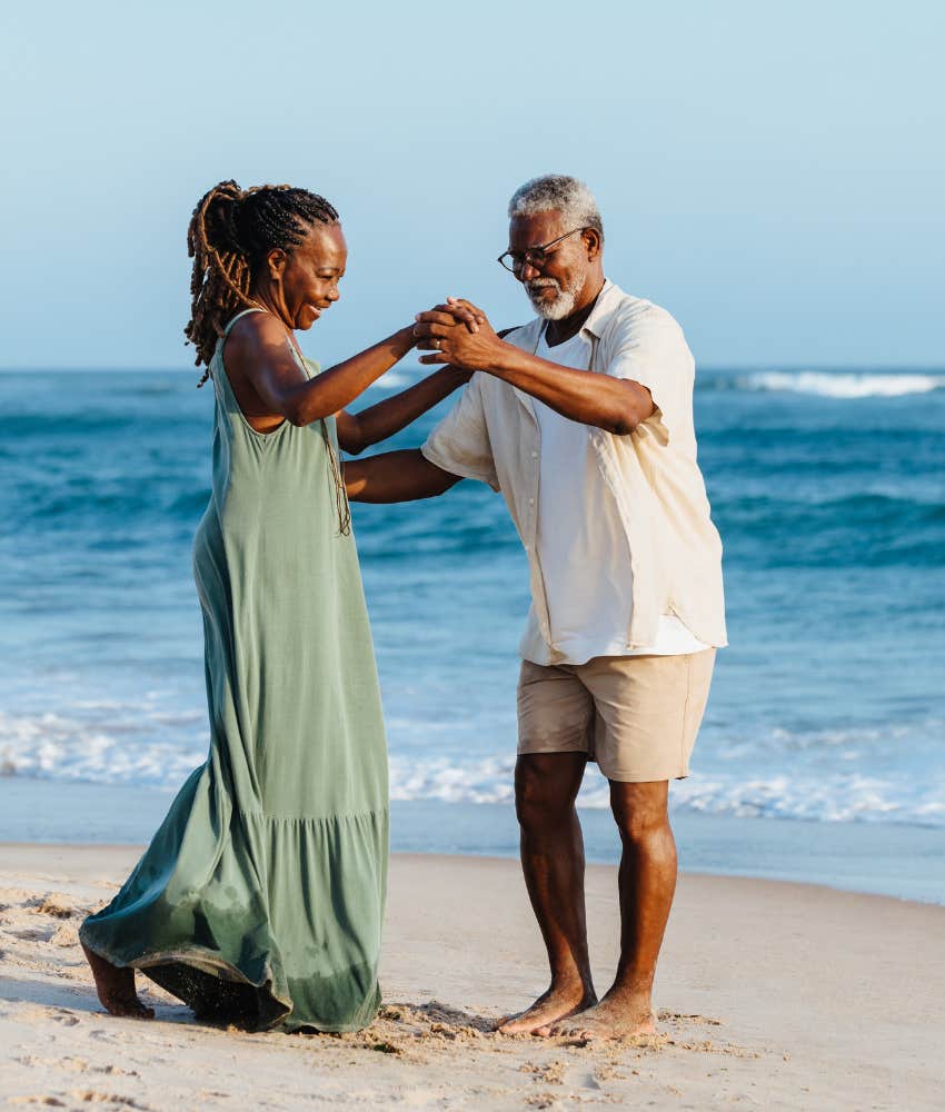 Happy empty nest couple dancing on the beach