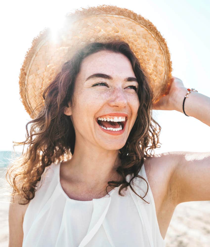 Happy smiling young woman wearing a hat at the beach