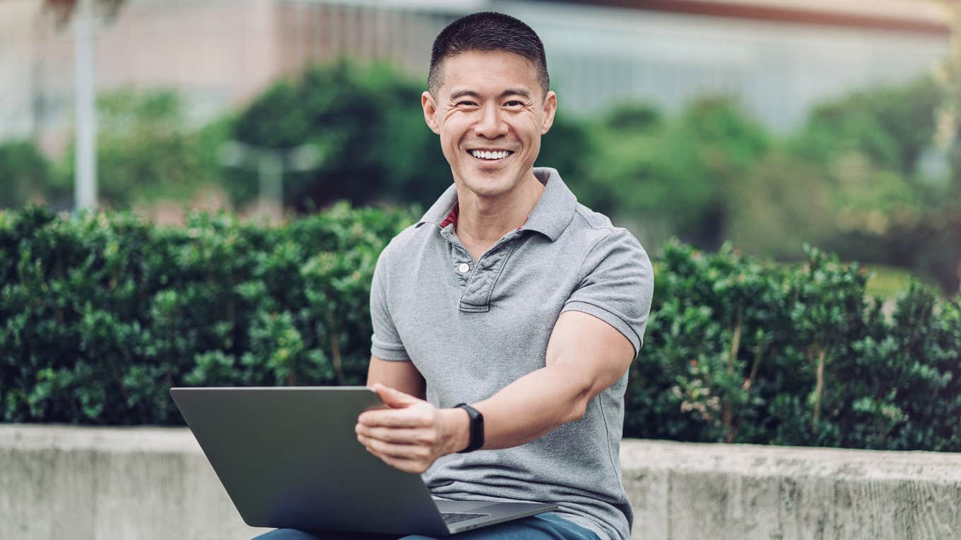 Harvard grad smiling while working on laptop