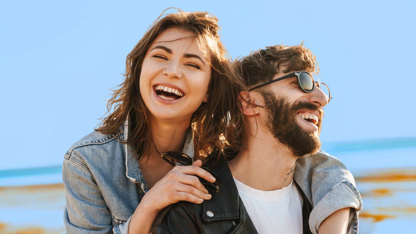 couple in a healthy relationship laughing at the beach