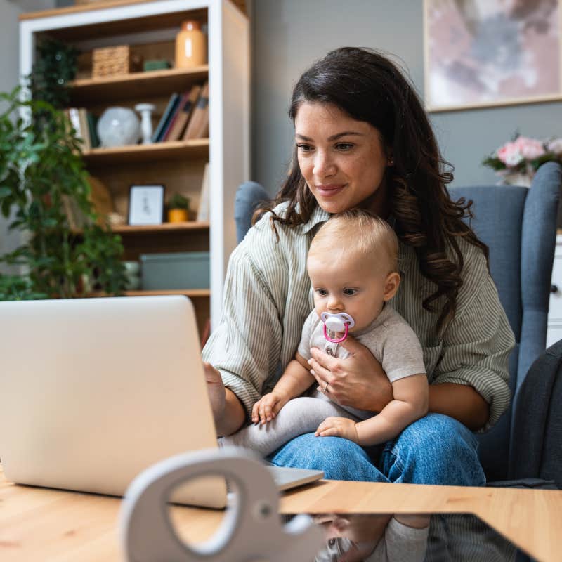 woman working on laptop with baby sitting in her lap