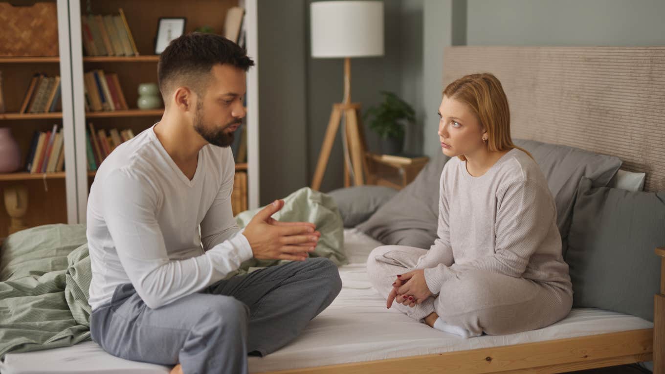 unhappy couple arguing while sitting on bed