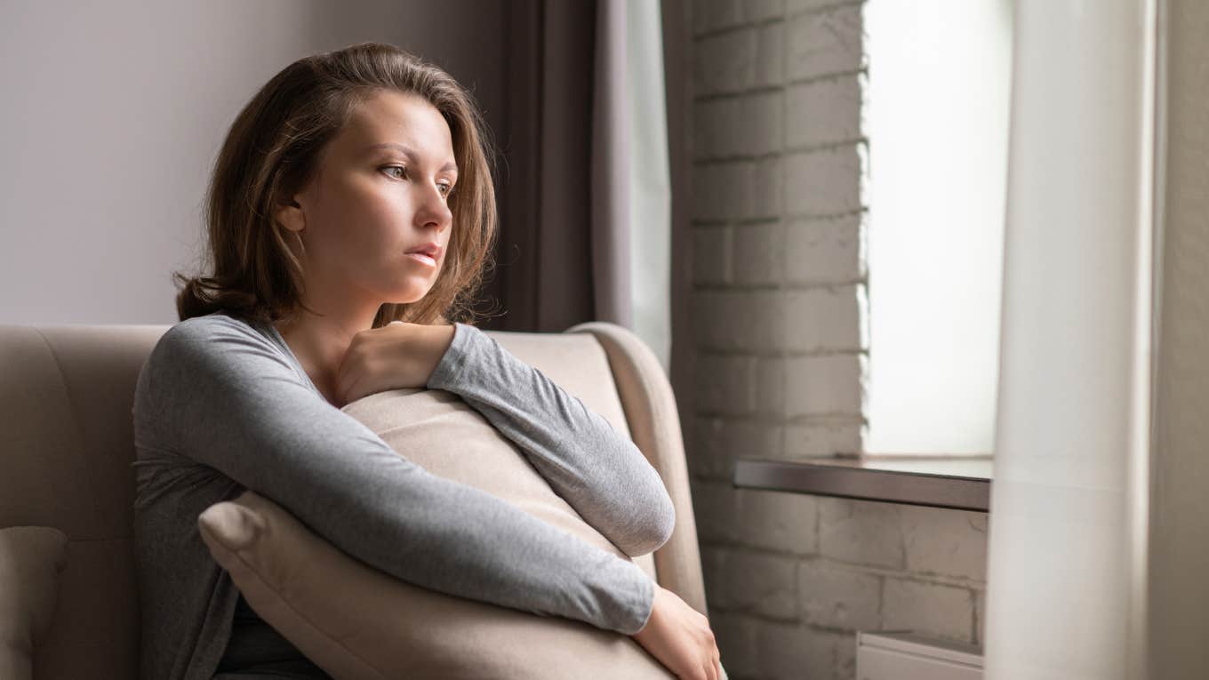 sad woman holding pillow to her chest