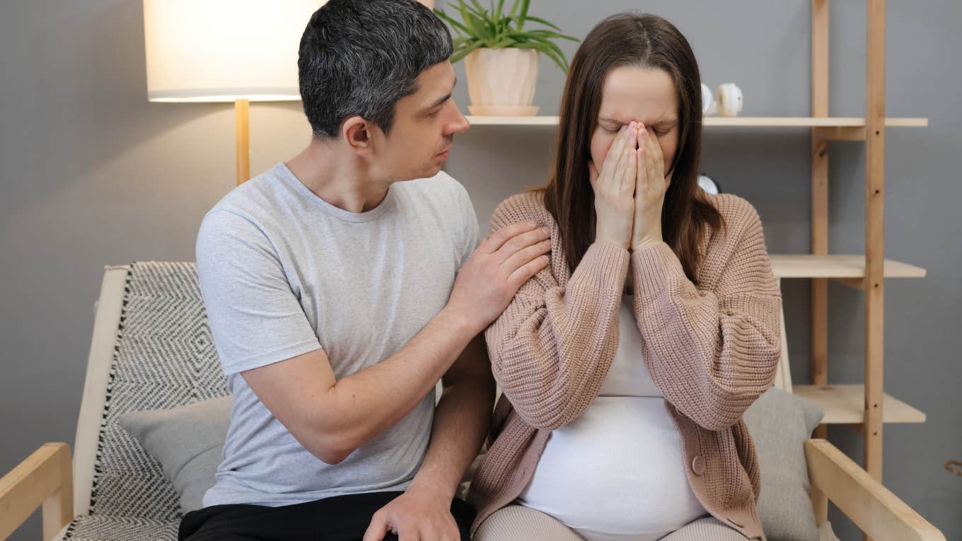 man trying to comfort an upset pregnant woman