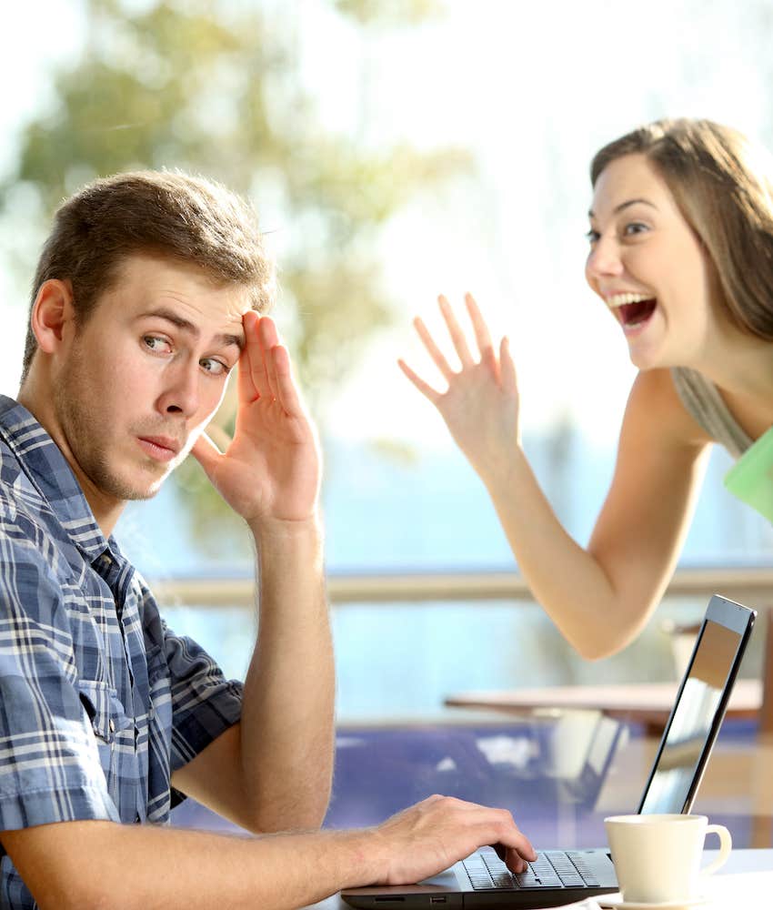 She waves through cafe window and he blocks his face with his hand