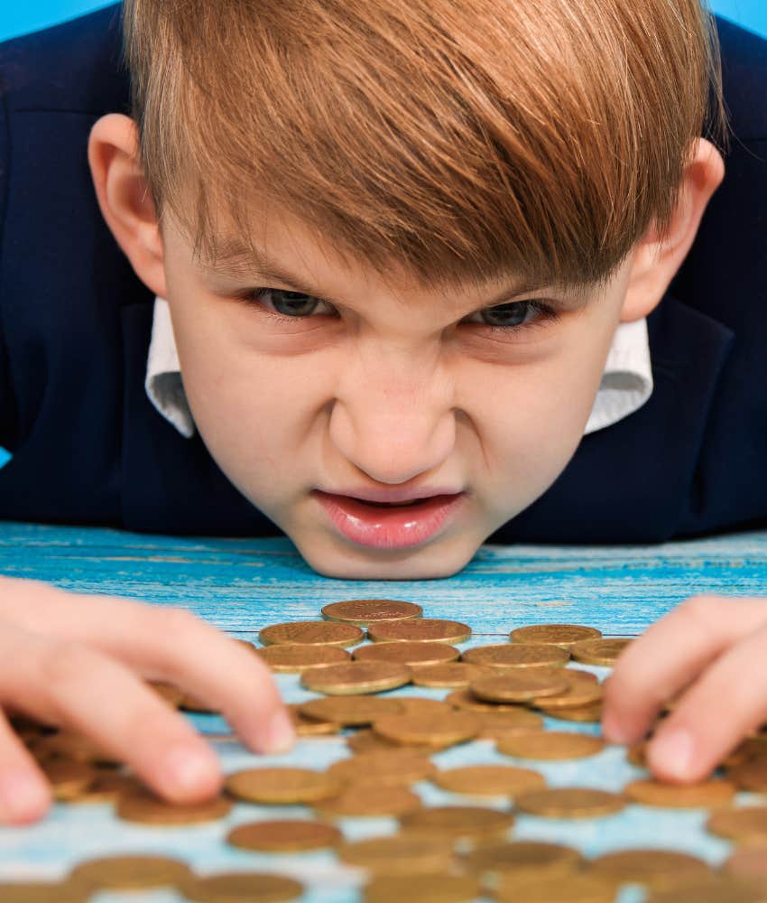 little boy looking angry with a bunch of coins