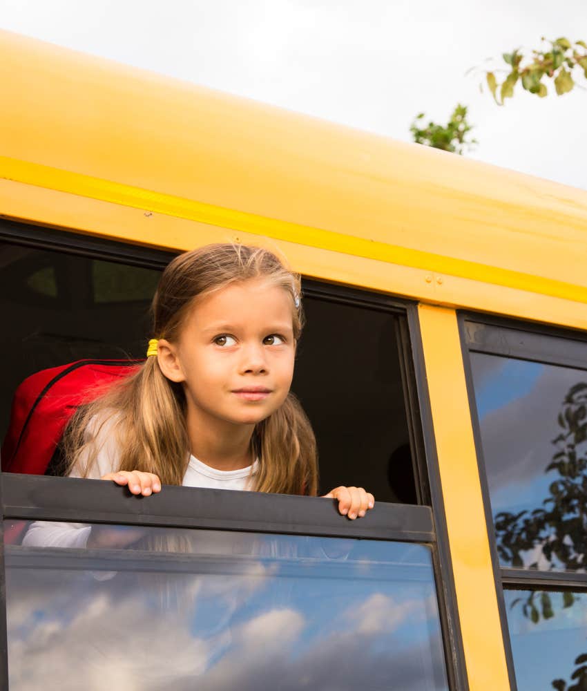 little girl looking out school bus window