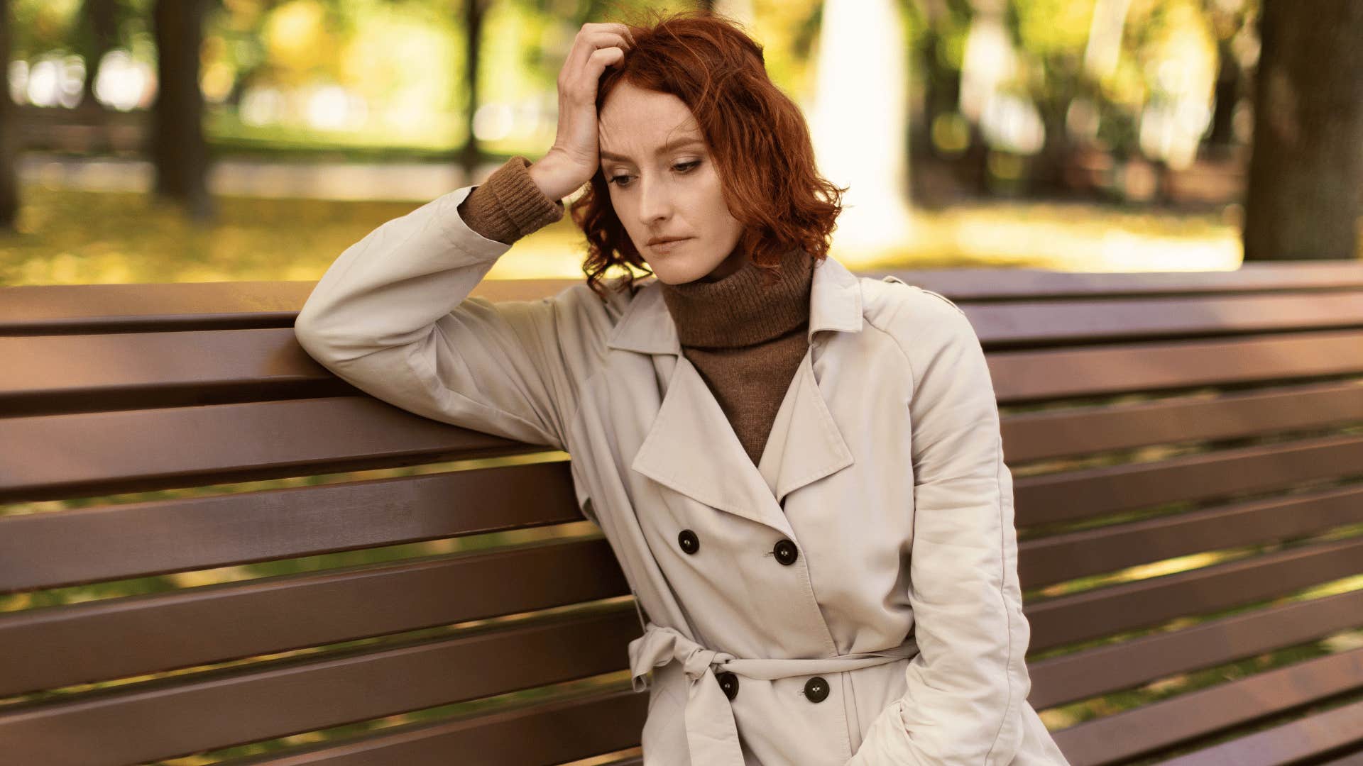 woman contemplating while sitting on a bench 