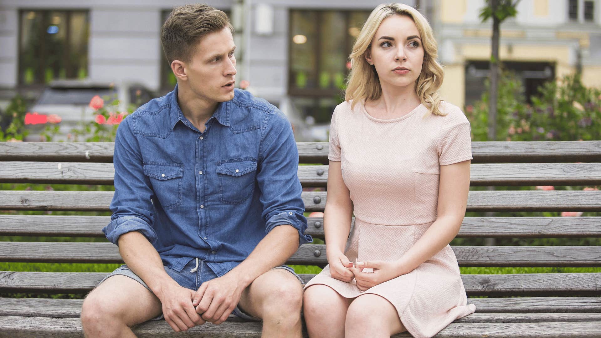 woman looking away from man upset while they sit on bench