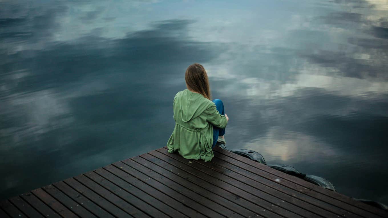 Woman sits alone in front of water