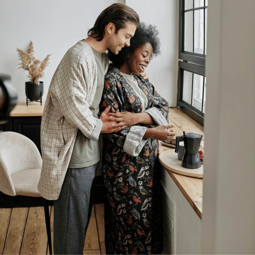 man hugging woman from behind in kitchen