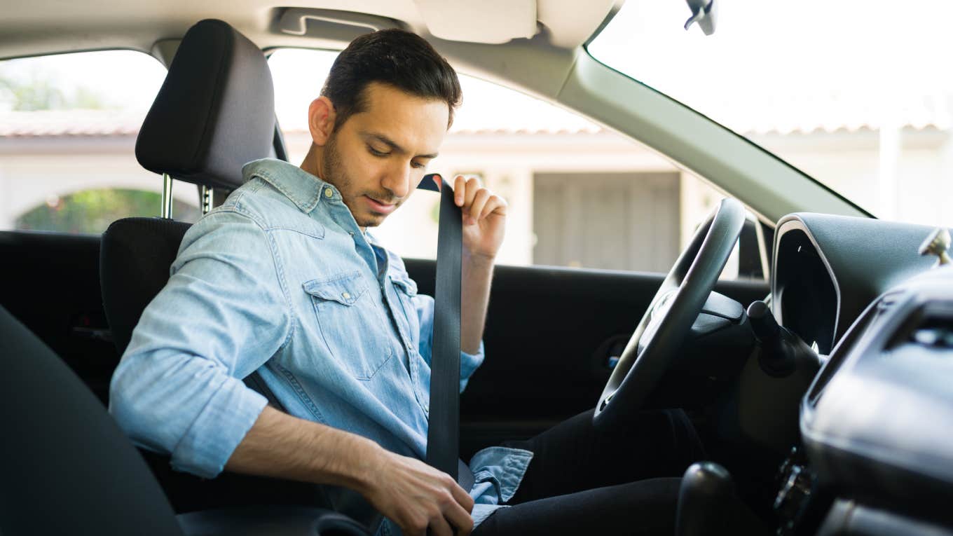 man buckling seatbelt in car while sitting behind wheel