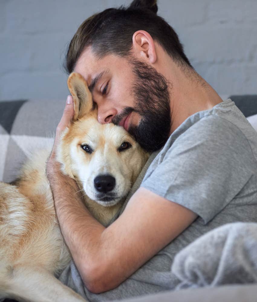 man snuggling with his dog